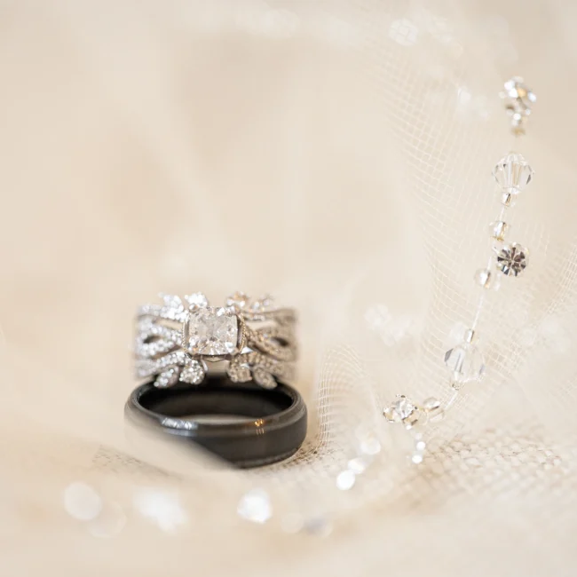 Close-up of wedding rings resting on lace with pearl details