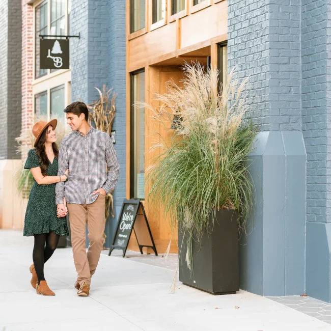 Couple walking hand in hand past downtown storefronts