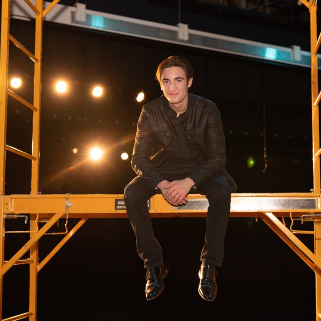 Senior guy sitting on stage scaffolding under theater lights