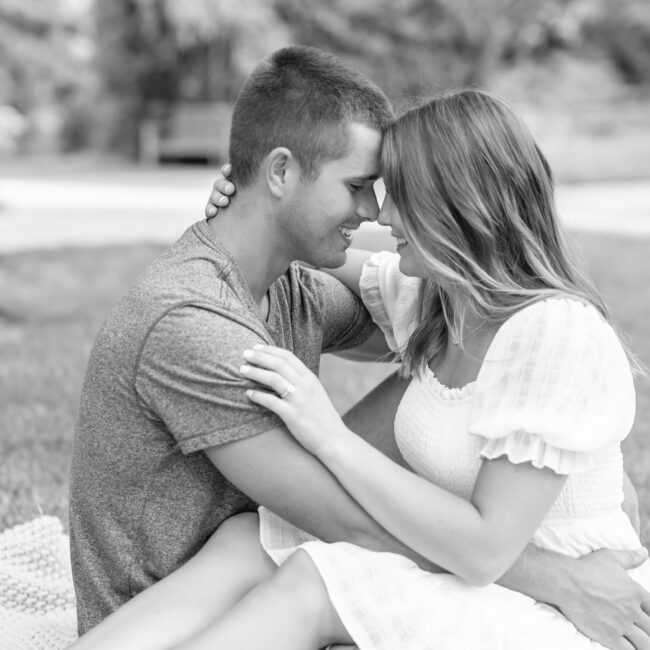 Black and white photo of a couple sitting close, foreheads touching