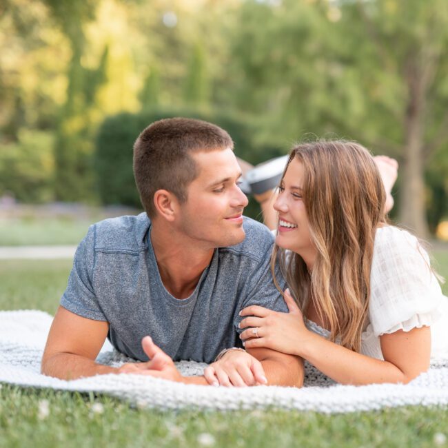 Couple lying on a blanket in the park, smiling at each other