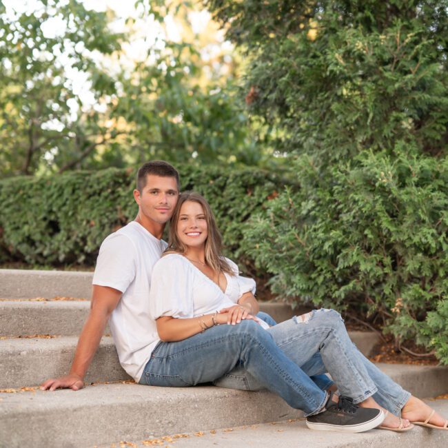 Couple sitting together on garden steps surrounded by greenery