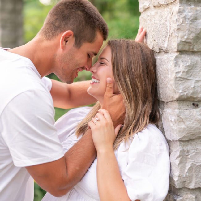 Couple sharing a close moment against a stone pillar