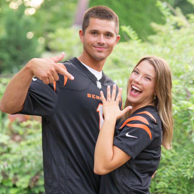 Couple in matching football jerseys showing off the engagement ring