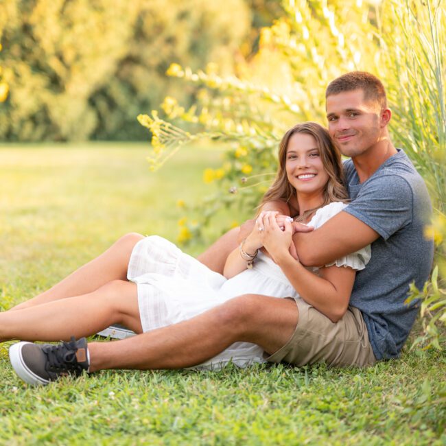 Couple relaxing together in the grass beside wildflowers