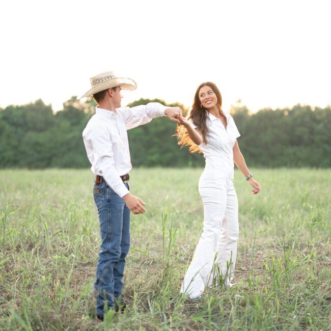 Couple dancing in a grassy field, him in a cowboy hat