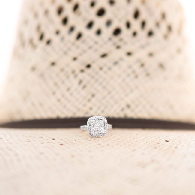 Engagement ring resting on the brim of a straw cowboy hat