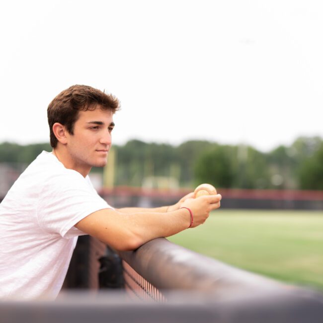Senior guy leaning on the baseball dugout railing
