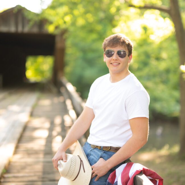 Senior guy with a cowboy hat and American flag on a covered bridge