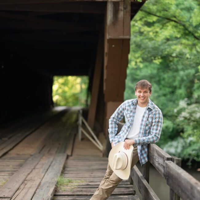 Senior guy in a plaid shirt leaning on the rail of a covered bridge